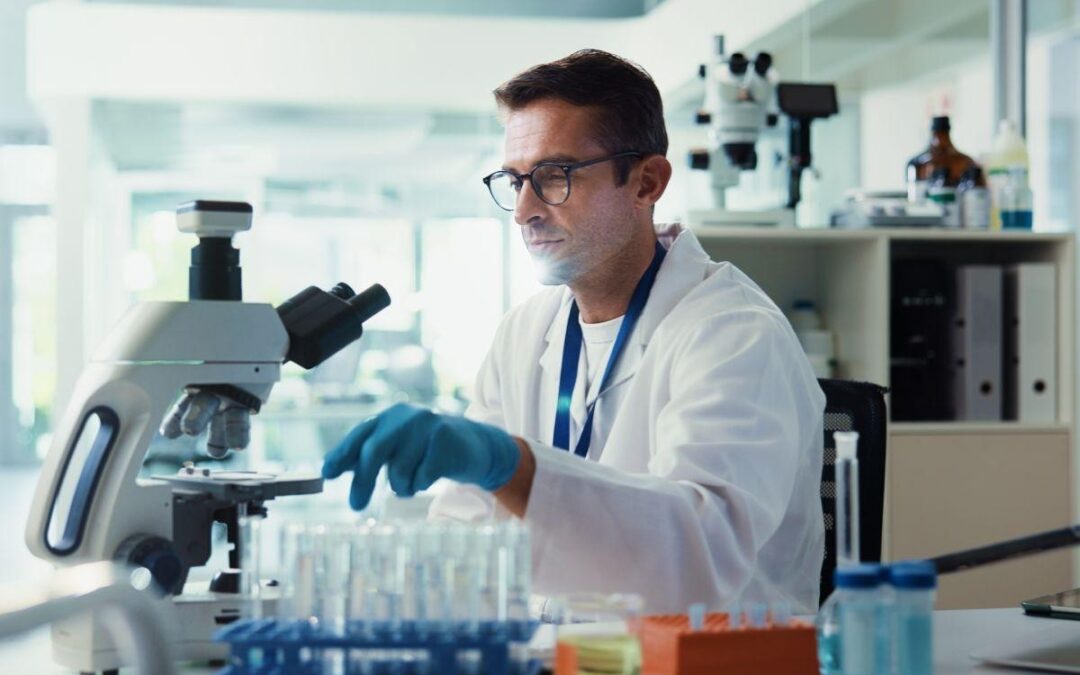 Male scientist examining samples with a microscope in a lab.