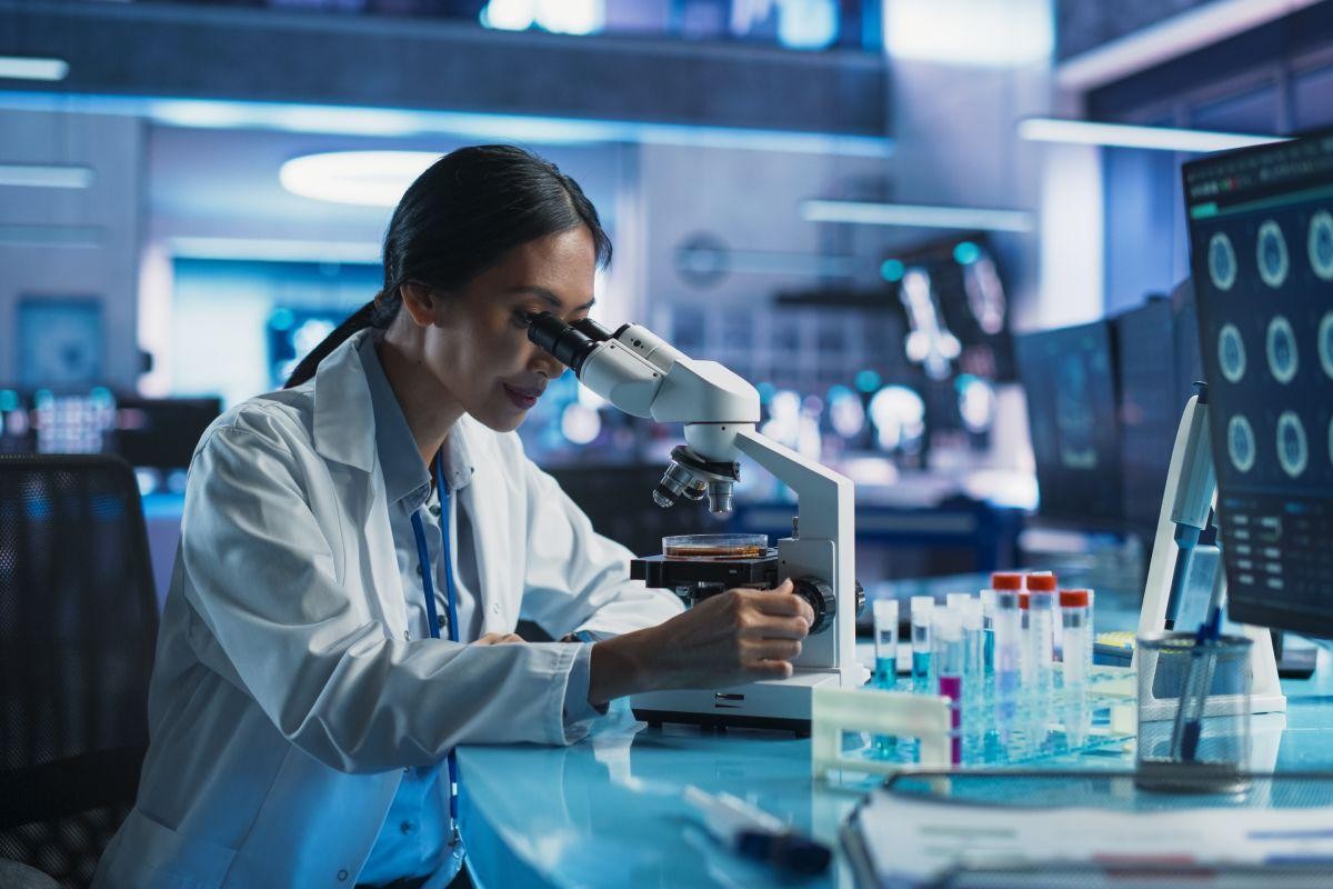 Scientist using a microscope in a laboratory environment.